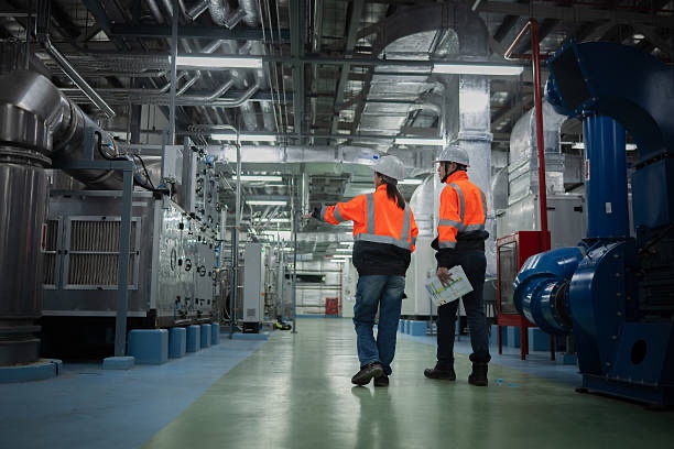 Two engineers in safety gear inspecting an industrial plant room